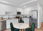 Thumbnail 9 of 29 - a kitchen with white cabinets and stainless steel appliances and a round table