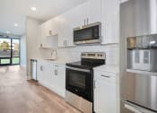 Thumbnail 9 of 38 - a kitchen with white cabinets and a stove and a microwave
