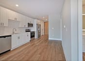 Thumbnail 11 of 38 - an empty kitchen with white cabinets and a wooden floor