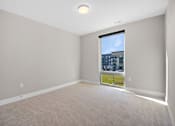 Thumbnail 32 of 38 - A room with a carpet floor and a window showing a view of a building.