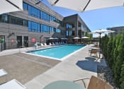 Thumbnail 28 of 38 - a swimming pool with lounge chairs and umbrellas in front of a building