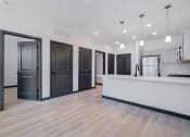 Thumbnail 11 of 29 - a kitchen and living room with a white counter top and black doors