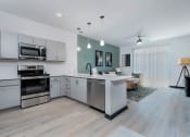 Thumbnail 1 of 29 - a kitchen and living room with white cabinets and stainless steel appliances