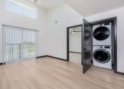 Thumbnail 14 of 29 - apartment living room with balcony sliding door and a washer and dryer