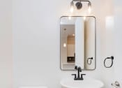 Thumbnail 13 of 40 - a bathroom with white walls and a white toilet next to a sink with a mirror above it