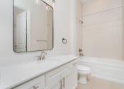 Thumbnail 23 of 40 - a bathroom with white cabinets and a white toilet next to a white bathtub with a shower