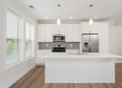 Thumbnail 15 of 40 - a kitchen with white cabinets and a large island