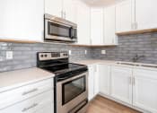 Thumbnail 3 of 40 - a kitchen with white cabinets and stainless steel appliances