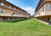 Thumbnail 25 of 29 - a row of apartment buildings with a grass yard