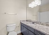 Thumbnail 8 of 42 - A bathroom with a toilet, sink, and mirror.