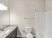 Thumbnail 9 of 42 - A white toilet sits in a bathroom next to a sink and a bathtub.