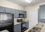 Thumbnail 14 of 42 - A kitchen with a black refrigerator and a white door.