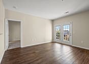 Thumbnail 20 of 42 - A room with a wooden floor and a door leading to another room.