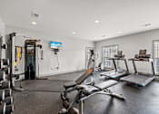 Thumbnail 31 of 42 - A home gym with a variety of equipment including a treadmill, weights, and a television.