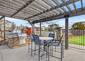 Thumbnail 35 of 42 - A patio with a table and chairs under a wooden pergola.