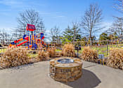 Thumbnail 36 of 42 - A playground with a red and blue slide and a circular stone structure in the middle.