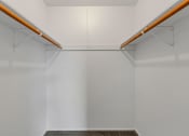 Thumbnail 24 of 38 - a walk in closet with white walls and two wooden rods hanging from the ceiling