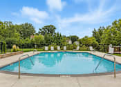 Thumbnail 12 of 45 - A swimming pool surrounded by trees and chairs.
