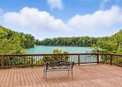 Thumbnail 13 of 45 - A bench sits on a wooden deck overlooking a lake.