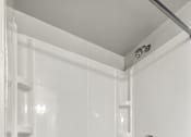 Thumbnail 23 of 45 - A white bathroom with a shower stall and a drain in the tub.