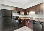 Thumbnail 28 of 45 - A black refrigerator is in a kitchen with wooden cabinets.