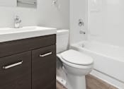 Thumbnail 29 of 45 - A white toilet sits next to a sink in a modern bathroom.