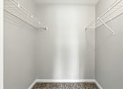 Thumbnail 32 of 45 - A walk-in closet with a carpeted floor and white walls.