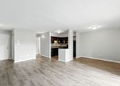 Thumbnail 34 of 45 - A large empty room with a kitchen area in the background.
