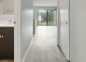 Thumbnail 35 of 45 - A long hallway with white walls and wood floors.