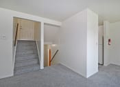Thumbnail 28 of 29 - a renovated living room with a carpeted staircase and white walls
