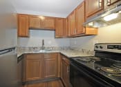 Thumbnail 5 of 29 - an empty kitchen with wood cabinets and black appliances