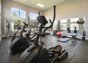 Thumbnail 17 of 23 - a gym with ellipticals and other exercise equipment in a building with windows