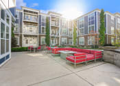 Thumbnail 8 of 27 - a patio with red couches and a table in front of an apartment building