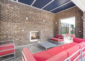 Thumbnail 11 of 27 - a patio with red couches and chairs and a fireplace