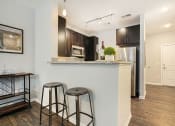 Thumbnail 21 of 27 - a kitchen with a bar with two stools and a refrigerator