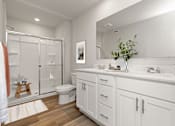 Thumbnail 7 of 8 - A white bathroom with a toilet, sink, and shower.