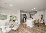 Thumbnail 9 of 32 - A dining table with white chairs and a glass top is in a room with a wooden floor.
