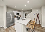 Thumbnail 3 of 32 - A kitchen with a refrigerator, microwave, and a counter with a chair.