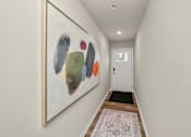 Thumbnail 24 of 32 - A hallway with a painting on the wall and a rug on the floor.