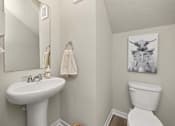 Thumbnail 20 of 32 - A white toilet sits next to a white sink in a bathroom.