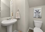 Thumbnail 21 of 32 - A white toilet sits next to a white sink in a bathroom.