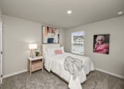 Thumbnail 14 of 32 - A bedroom with a bed, nightstand, and two pictures on the wall.