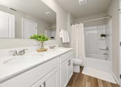 Thumbnail 18 of 32 - A white bathroom with a plant on the counter.