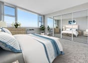 Thumbnail 5 of 26 - a bedroom with large windows and a bed with blue and white bedding