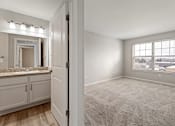 Thumbnail 41 of 43 - A carpeted room with a window and a bathroom visible through the door.