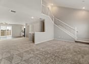 Thumbnail 42 of 43 - A spacious living room with a staircase and a kitchen area in the background.