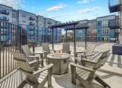 Thumbnail 40 of 41 - an outdoor patio with chairs and a fire pit and an apartment building