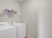Thumbnail 18 of 41 - a white washer and dryer in a laundry room with a shelf above it