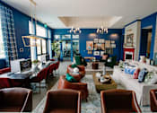 Thumbnail 21 of 43 - A living room with a white couch, red chairs, and a coffee table.