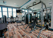 Thumbnail 31 of 43 - A gym with a variety of equipment including a squat rack, bench, and weights.